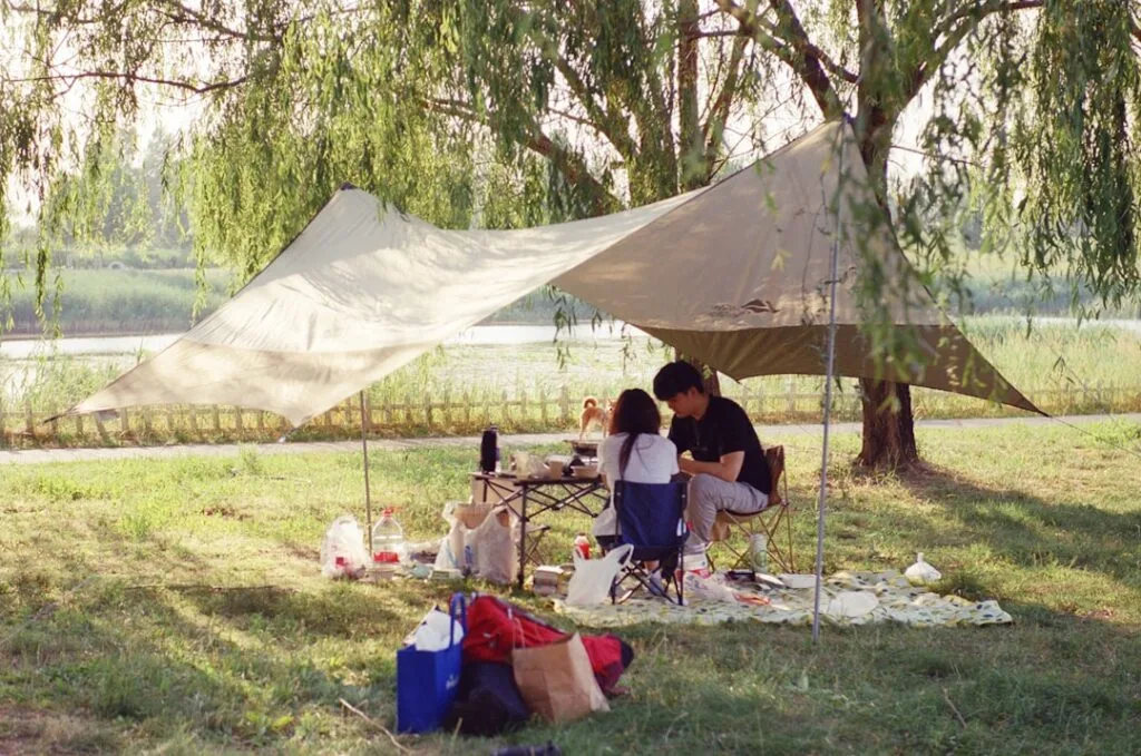 Pärchen beim Picknick unter einem Schutzdach nahe eines schattigen Teichs