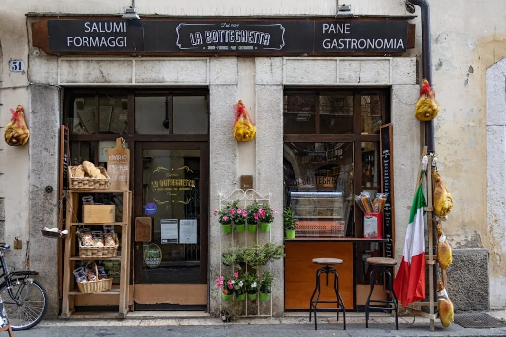 Fassade der Feinkost La Botteghetta in Verona, hängende Schinken und Brot