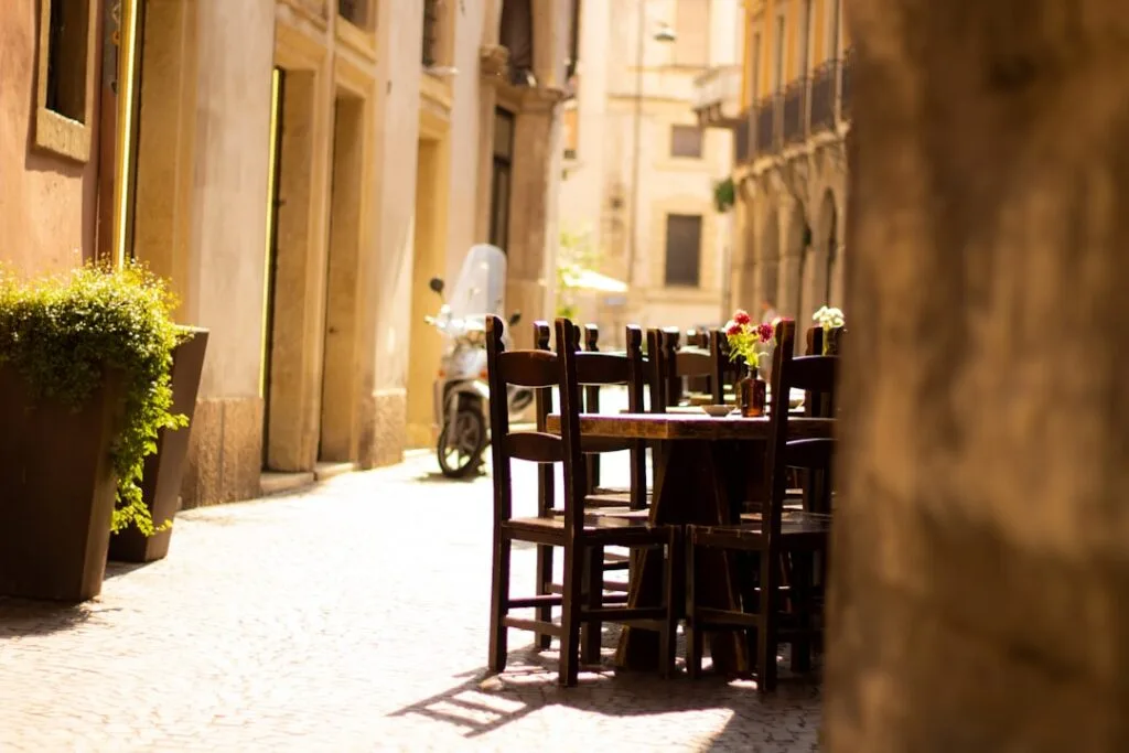 Straßencafé mit Holztischen und Rollermoped in einer Gasse Veronas