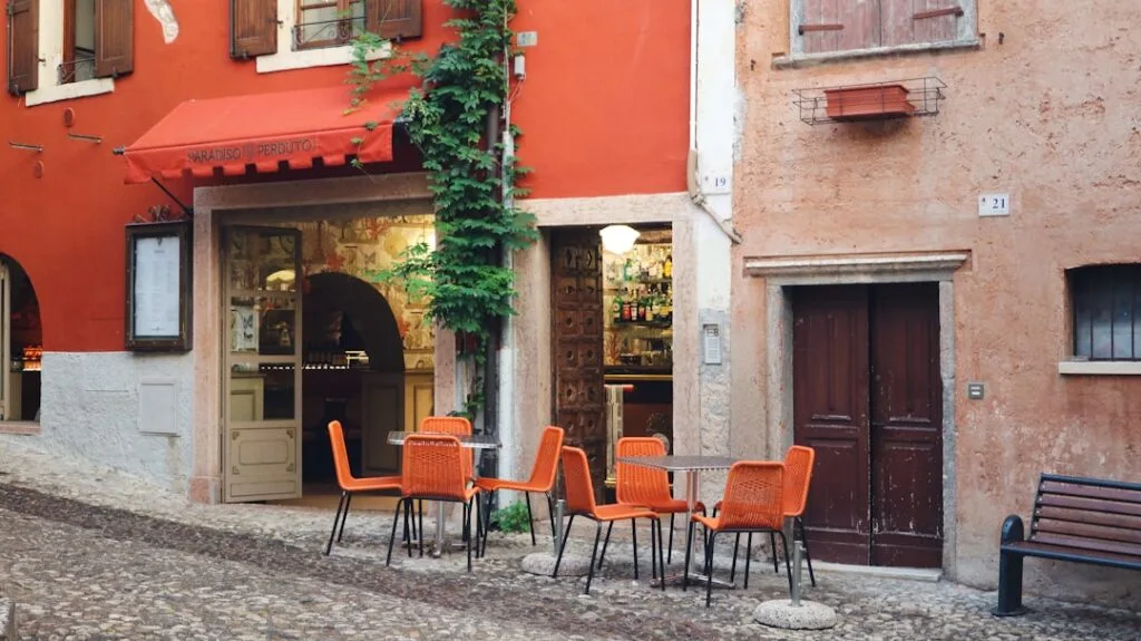 Kleines Café mit orangen Stühlen in verwinkelter Gasse Veronas.