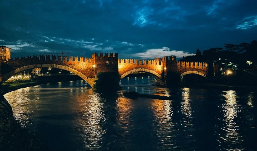 Beleuchtete Scaligerbrücke über den ruhig reflektierenden Fluss in Verona