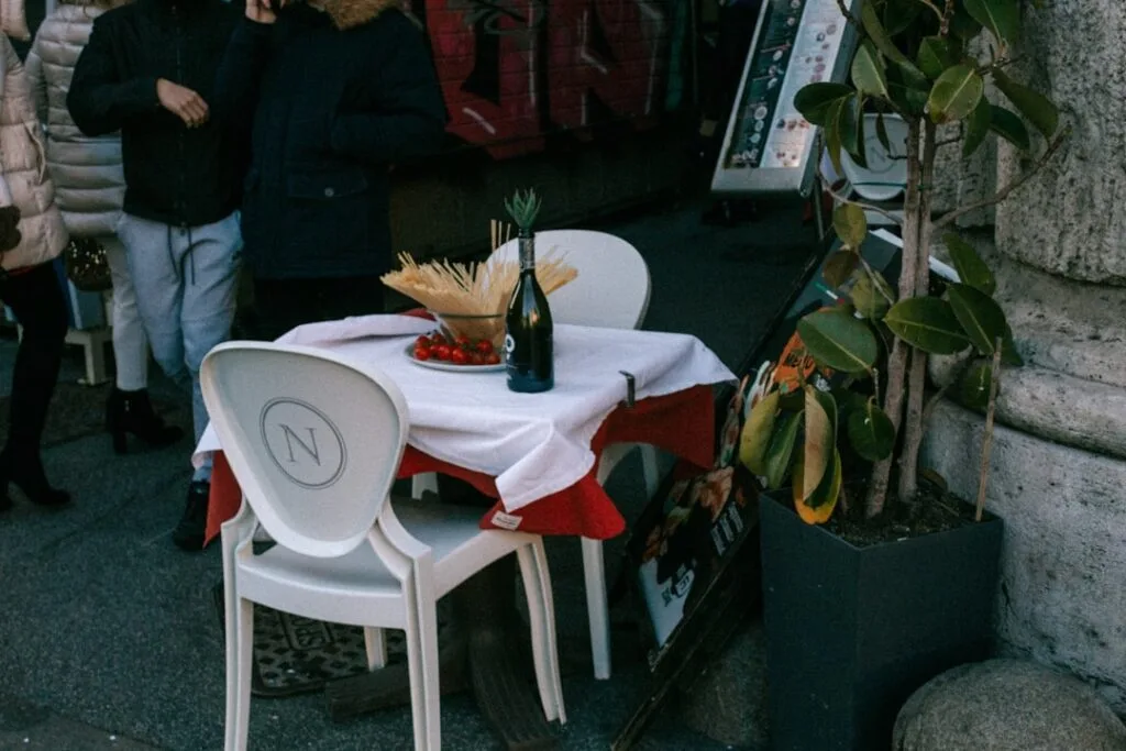 Veronisches Bistro-Tischchen mit Flasche, Tomaten und weißen Stühlen