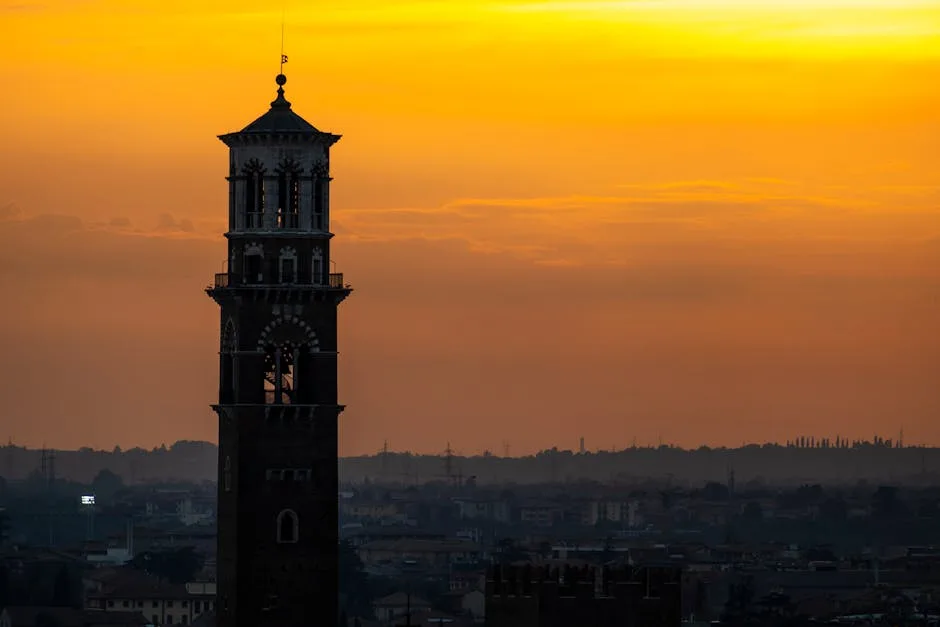 Silhouette eines Glockenturms in Verona vor orangefarbenem Sonnenuntergang