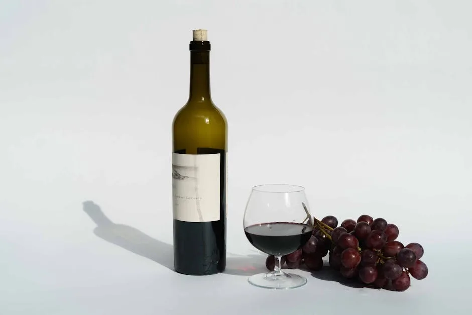 Weinflasche, Glas mit Rotwein und Trauben auf weißem Hintergrund