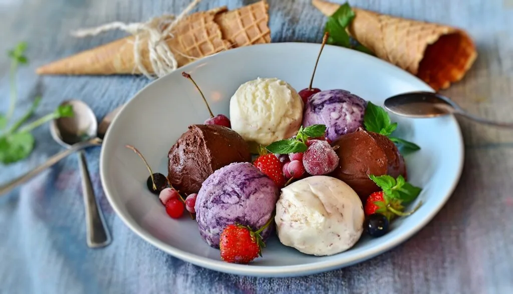 Mehrere bunte Eiskugeln mit Beeren und Waffeln, Gelato in Verona