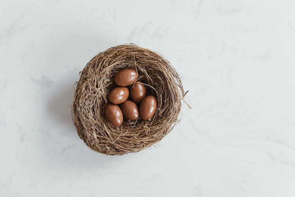 Vogelnest mit schokoladenüberzogenen Ostereiern auf hellem Marmortisch