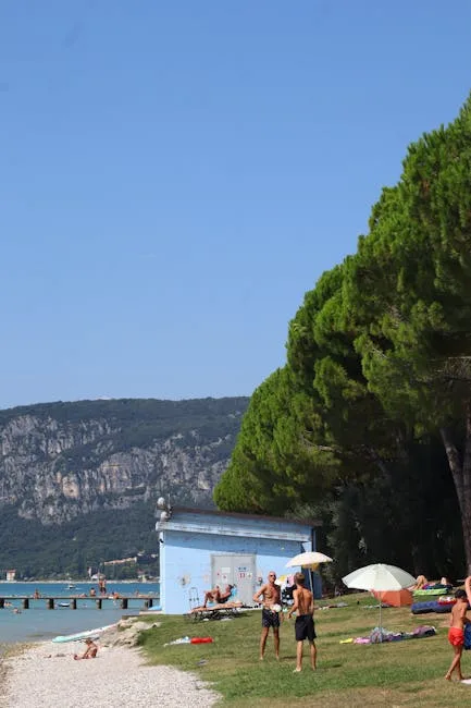 Familien am Kiesstrand unter Pinien am Gardasee bei Sirmione