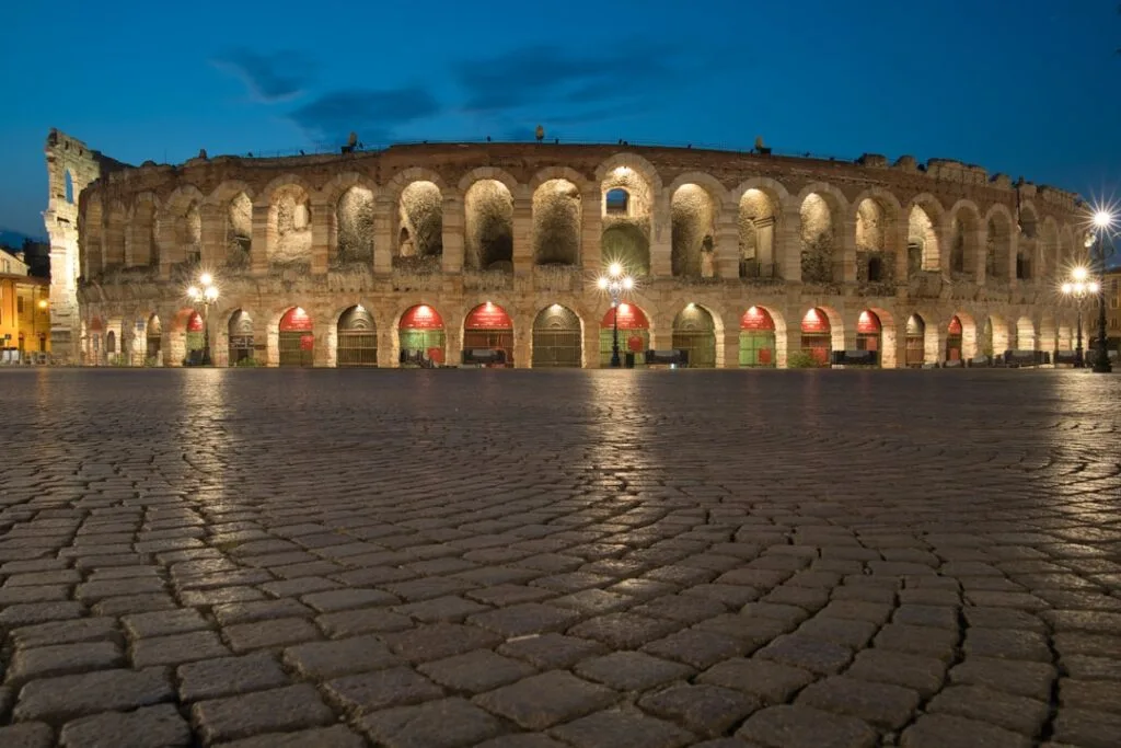 Beleuchtete Arena von Verona bei Abenddämmerung auf dem gepflasterten Platz