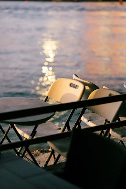 Leere Plastiksessel am Ufer mit Lichtreflexen im Wasser von Verona