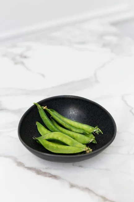 Gousses de pois vertes dans un bol noir sur table en marbre