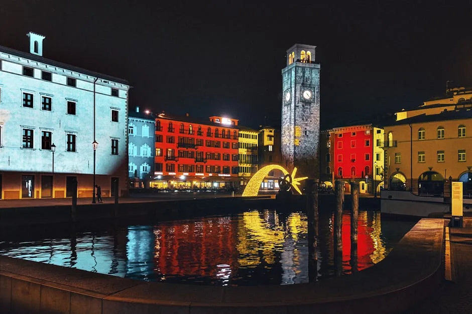 Place du port de Riva del Garda la nuit, tour horloge et reflets colorés