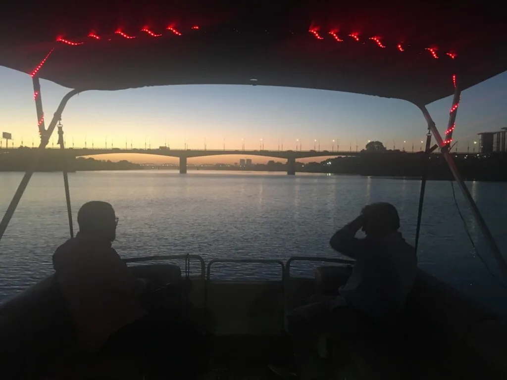 Zwei Personen als Silhouetten im Boot bei Dämmerung, Brücke im Hintergrund