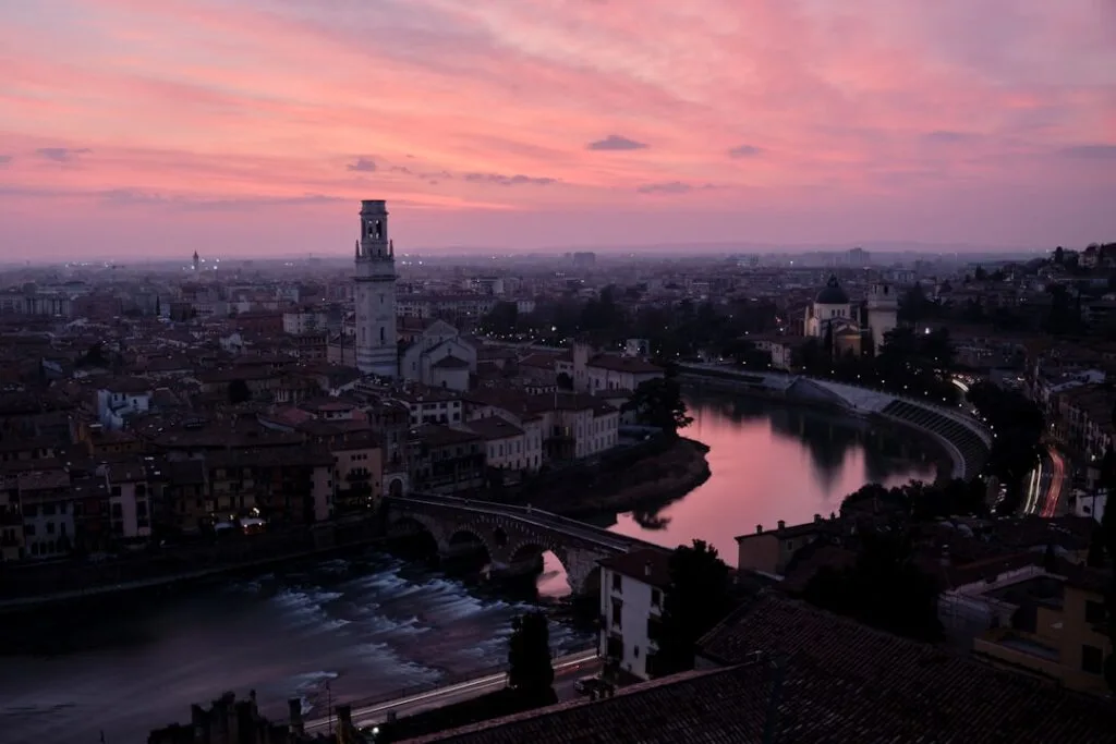 Verona bei Sonnenuntergang mit Fluss, steinerner Brücke und Glockenturm.