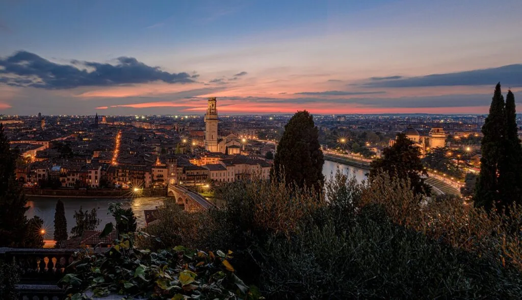 Panoramablick bei Dämmerung auf Verona mit beleuchteter Brücke und Fluss