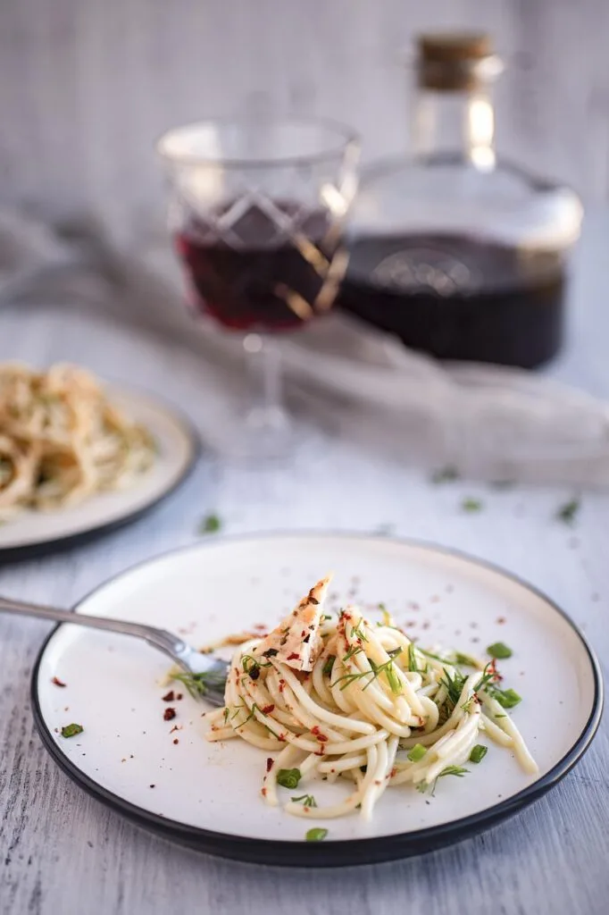 Teller mit Spaghetti, Gabel und Glas Rotwein im Hintergrund in Verona