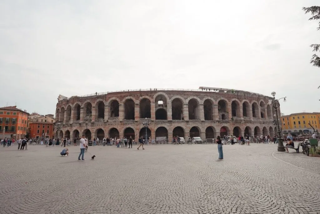 Façade extérieure de l'arène de Vérone bordée d'une place animée
