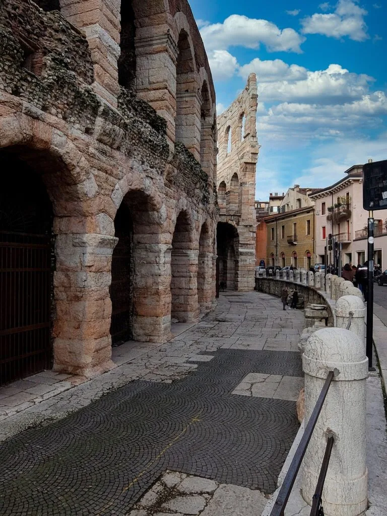 Façade extérieure de l'Arena de Vérone le long d'une rue pavée